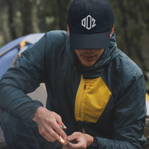 A man outdoor camping in forest and wearing Outdoorz logo hatA man outdoor camping in forest and wearing Outdoorz logo hat
