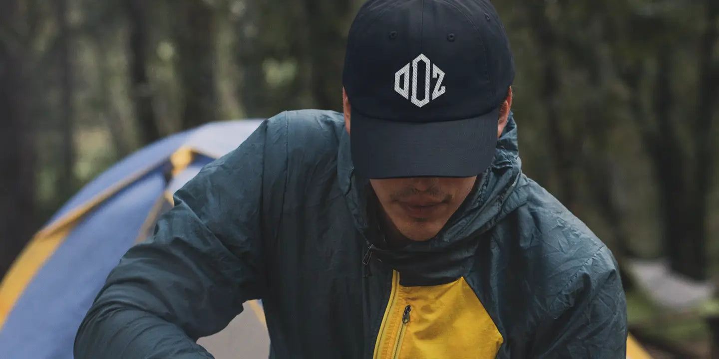 A man outdoor camping in forest and wearing Outdoorz logo hat